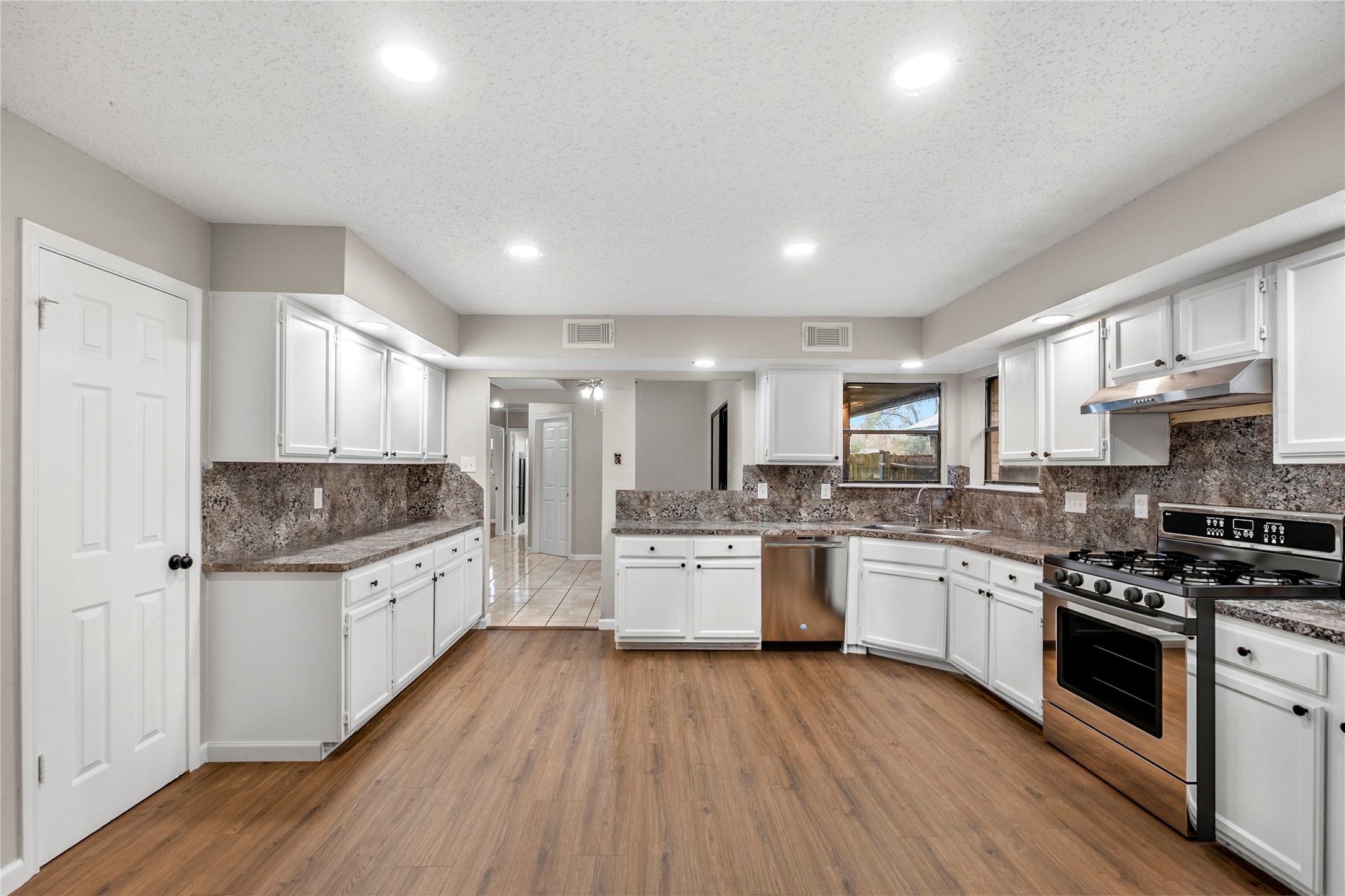 20066 Moonflower Lane Katy, TX 77449 - Photo 7 of 20 a large kitchen with granite countertop a stove top oven a sink dishwasher a dining table and chairs with wooden floor