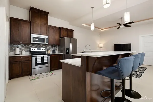 a kitchen with stainless steel appliances granite countertop a stove a refrigerator a sink a dining table and chairs with wooden floor