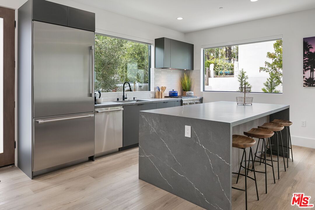 1236 North Spaulding Avenue, Unit 3 West Hollywood, CA 90046 - Photo 2 of 20 a kitchen with kitchen island a counter top space a sink a refrigerator and a large window