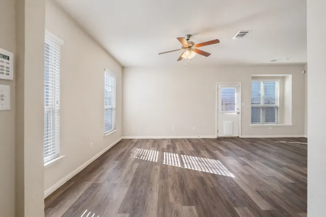a view of empty room with wooden floor and fan
