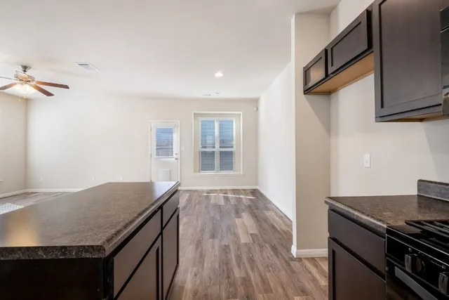 a kitchen with granite countertop a stove cabinets and wooden floor