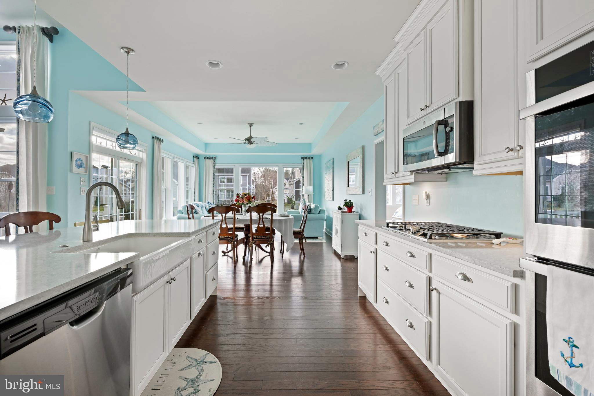 34017 Smiths Point Lane Lewes, DE 19958 - Photo 17 of 66 a kitchen with stainless steel appliances granite countertop a stove top oven a sink a dining table and chairs with wooden floor