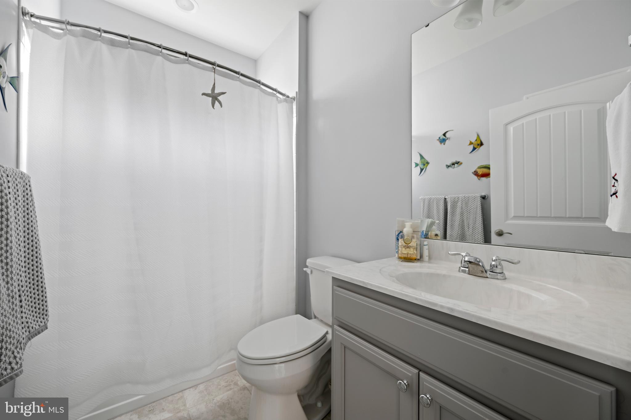34017 Smiths Point Lane Lewes, DE 19958 - Photo 35 of 66 a bathroom with a sink a toilet and shower curtain
