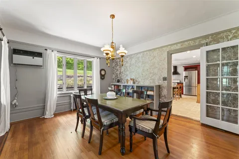 a kitchen with stainless steel appliances granite countertop a stove a refrigerator a sink a dining table and chairs with wooden floor