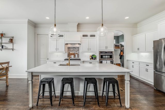 a kitchen with stainless steel appliances granite countertop a table chairs stove refrigerator and cabinets