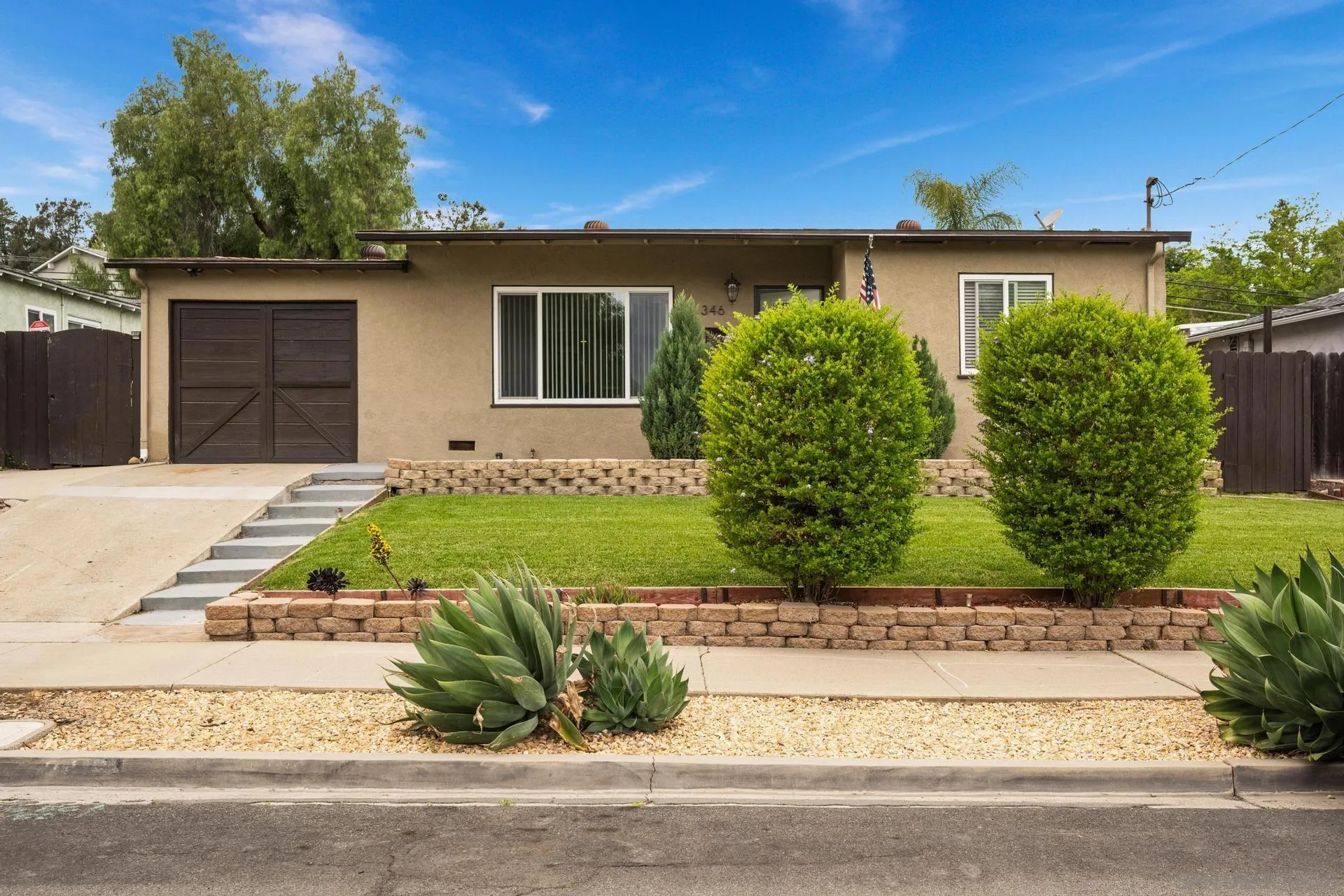 a view of a house with a yard and potted plants