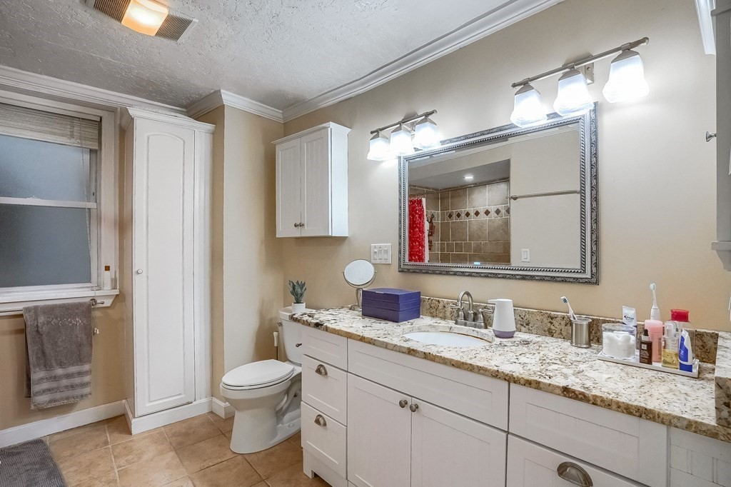 22 James Street, Unit 1 Brookline, MA 02446 - Photo 16 of 24 a bathroom with a granite countertop toilet sink and mirror