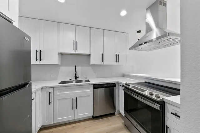 a kitchen with white cabinets stainless steel appliances and sink