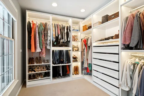 a view of walk in closet with clothes and shoes