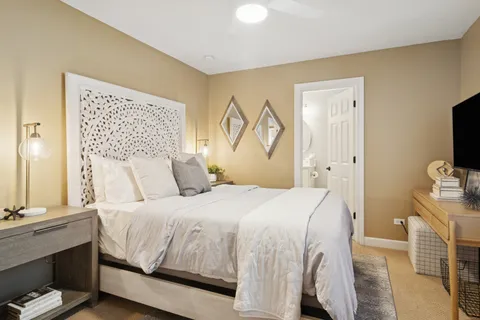 a bedroom with a bed and a flat tv screen on dresser