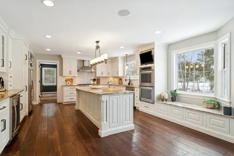 a large kitchen with stainless steel appliances kitchen island granite countertop a large counter top and a stove