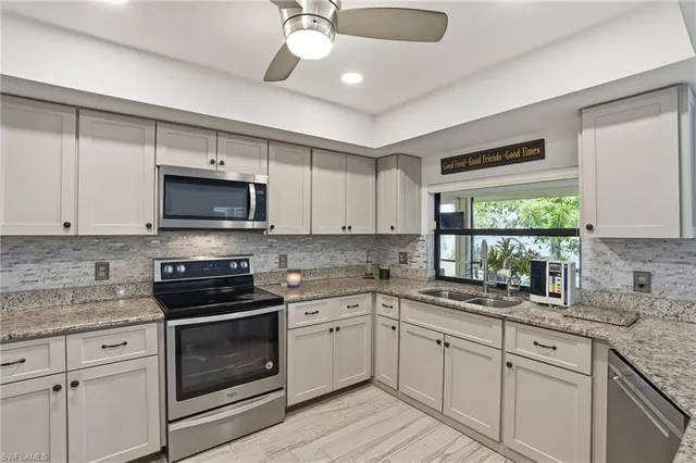 a kitchen with white cabinets appliances a sink and a window