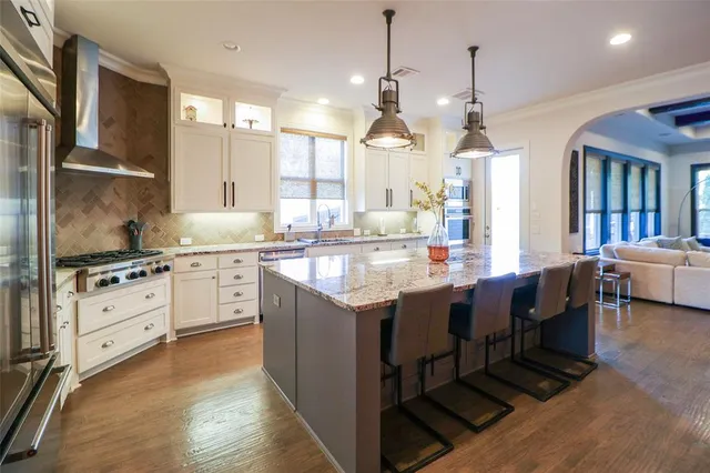a kitchen with stainless steel appliances kitchen island granite countertop a table chairs and a refrigerator