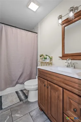 a bathroom with a sink a toilet and shower curtain