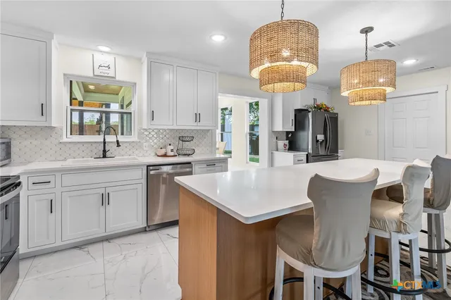 a kitchen with stainless steel appliances granite countertop a table chairs and a sink