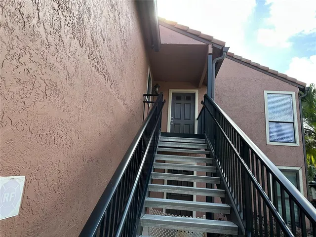 a view of a house with a yard and potted plants