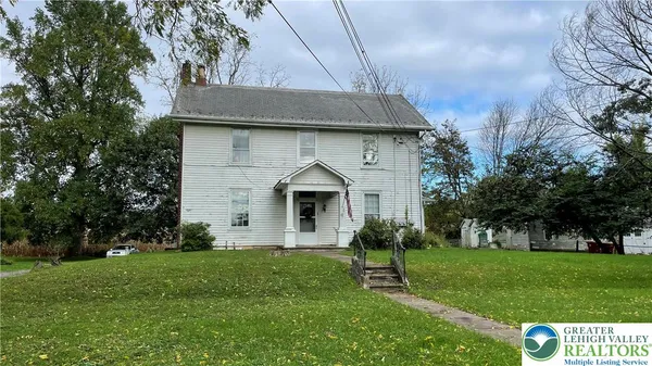 a front view of a house with a yard and trees