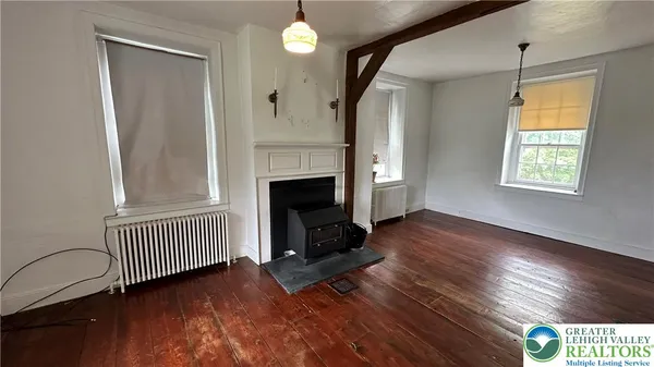 an empty room with wooden floor fireplace and windows