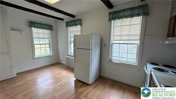 a view of an empty room with a window and wooden floor