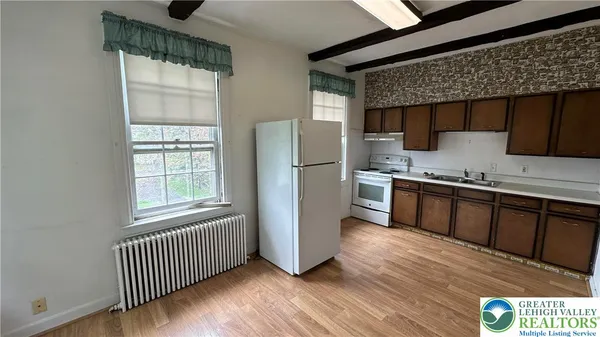 a kitchen with stainless steel appliances granite countertop a refrigerator a sink dishwasher a stove and white countertops with wooden floor