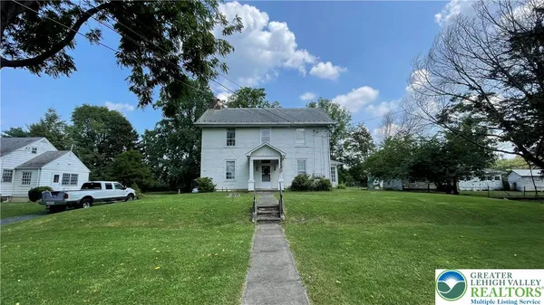 a front view of a house with a garden and trees
