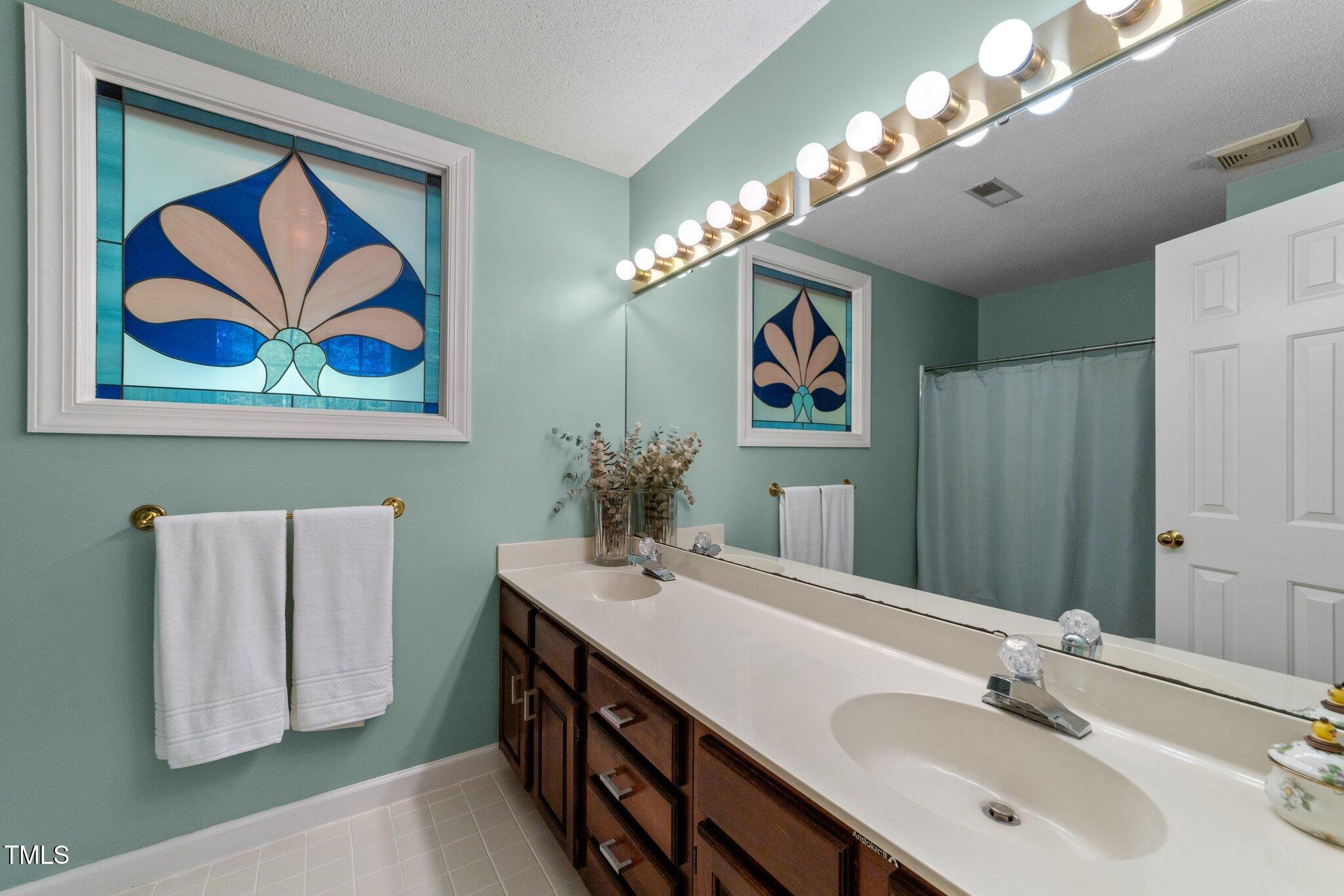 12200 Glenlivet Way Raleigh, NC 27613 - Photo 21 of 51 a bathroom with a sink a vanity and a mirror