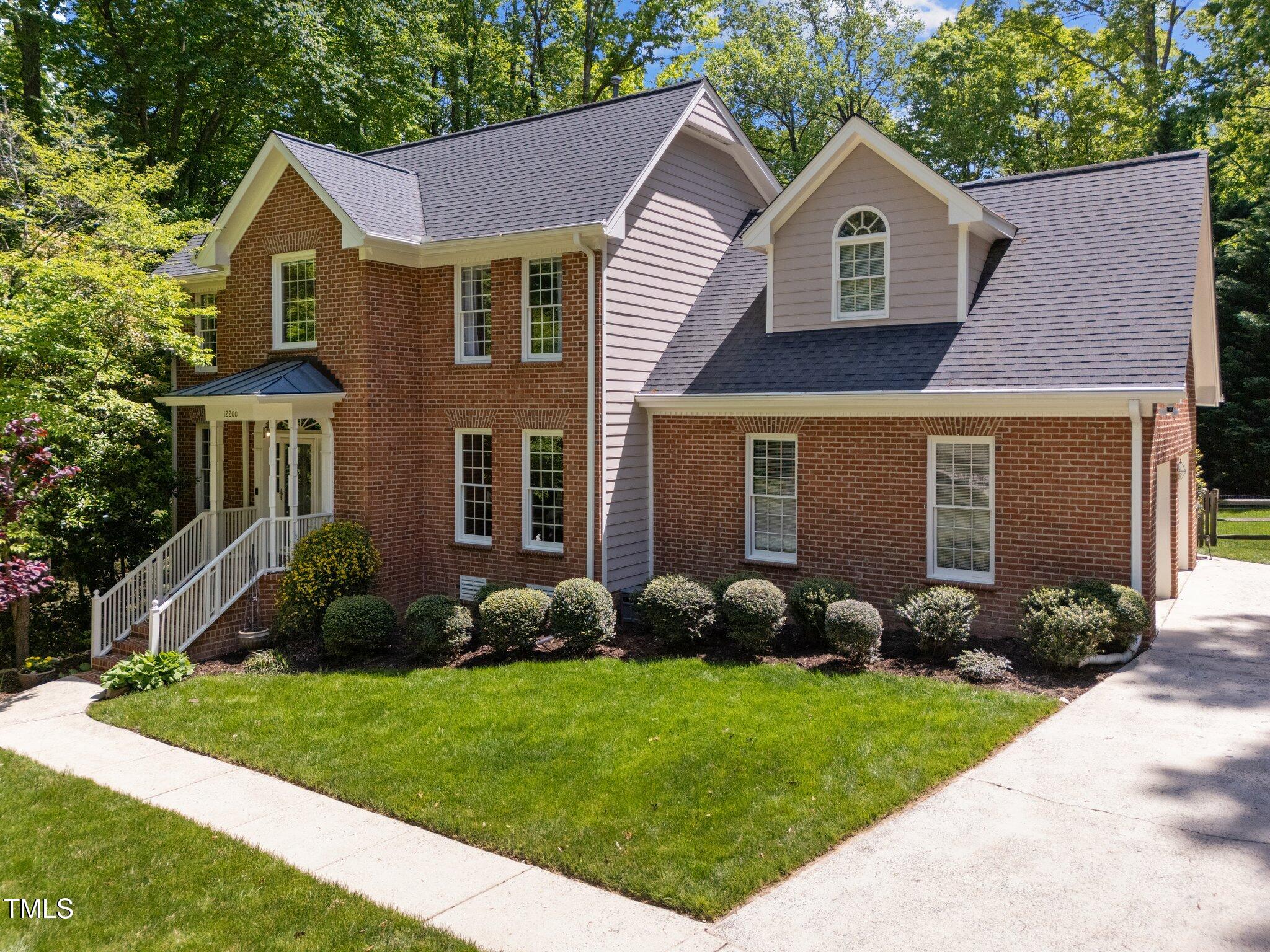 12200 Glenlivet Way Raleigh, NC 27613 - Photo 2 of 51 a view of a yard in front of a brick house with plants and large tree