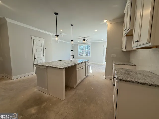 a kitchen with kitchen island granite countertop a sink a counter top space and stainless steel appliances
