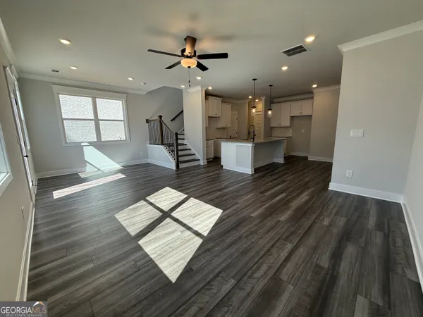 a living room with stainless steel appliances furniture a rug and a kitchen view