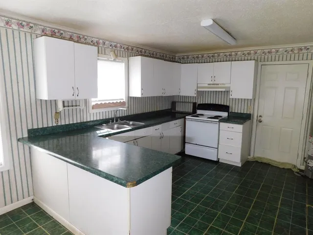 a kitchen with stainless steel appliances a sink a stove a refrigerator a window and white cabinets