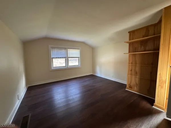 an empty room with wooden floor cabinet and windows