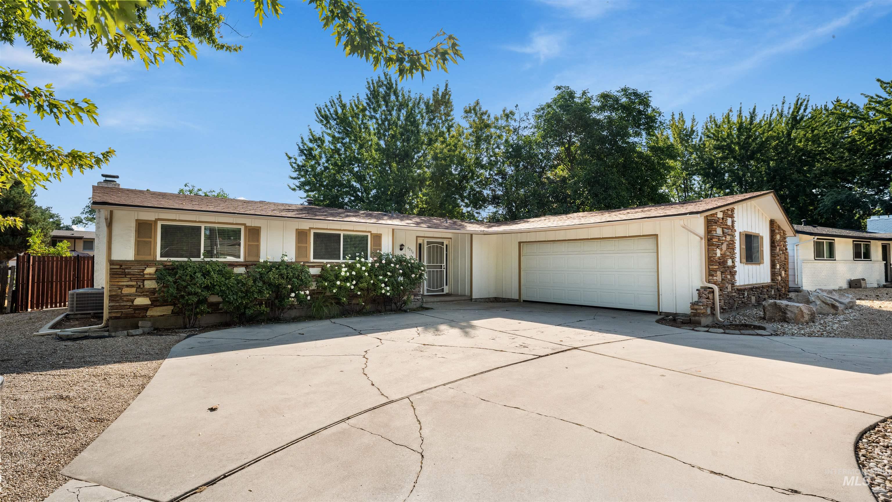 4054 North Maple Grove Road Boise, ID 83704 - Photo 1 of 34 Stone veneer facade, attached garage, concrete driveway, mature landscaping, and front entry with security screen door