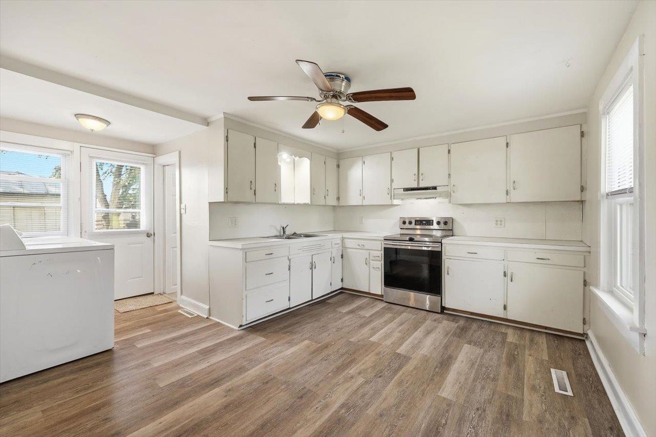 5096 Battlefield Road Harrisonburg, VA 22801 - Photo 12 of 38 a kitchen with stainless steel appliances white cabinets a sink a stove a refrigerator and island with wooden floor