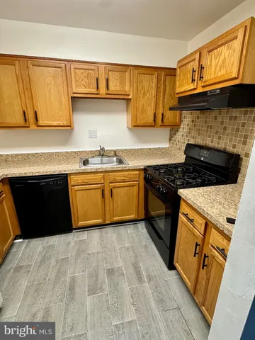 a kitchen with granite countertop a sink a stove and cabinets