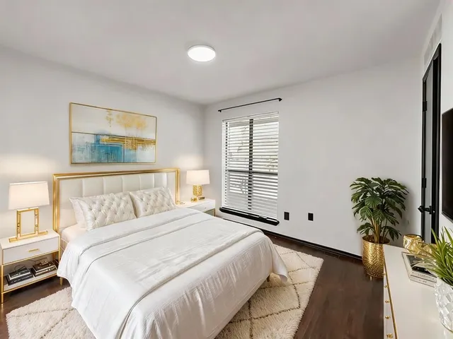 a large bed sitting in a bedroom next to a window with potted plants