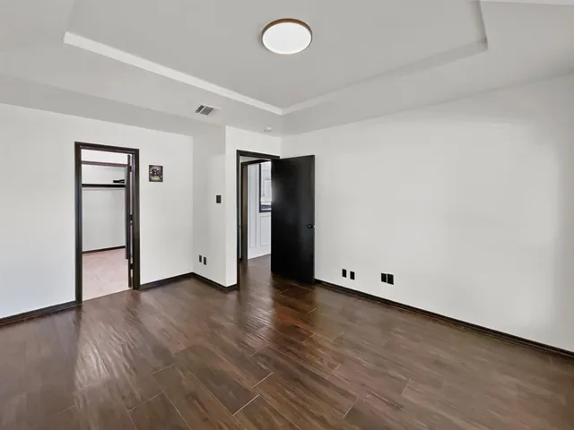 a view of an empty room with wooden floor and closet