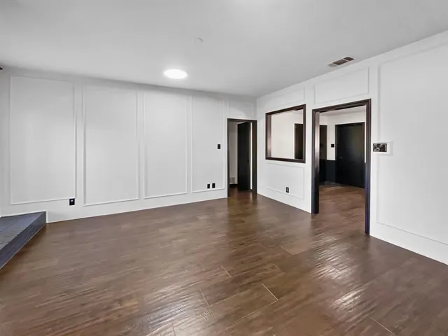 a view of an empty room with wooden floor and closet