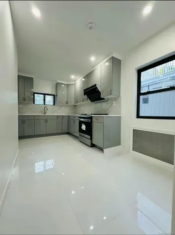 a large white kitchen with stainless steel appliances a large counter top