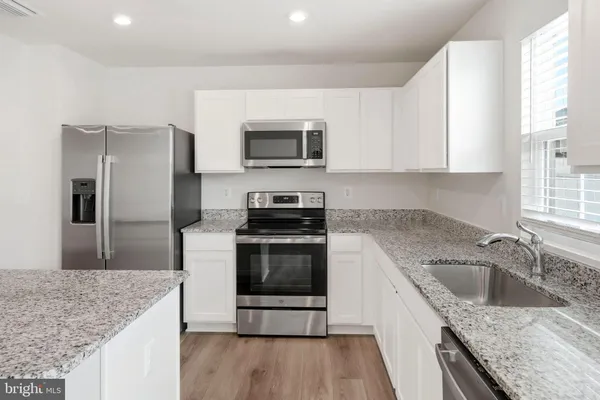 a kitchen with stainless steel appliances granite countertop a sink stove refrigerator and cabinets
