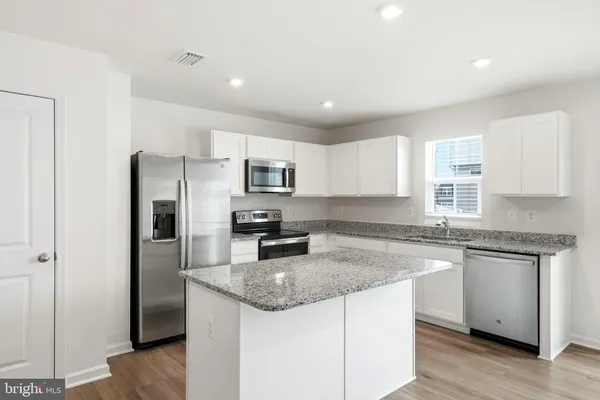 a kitchen with stainless steel appliances granite countertop a refrigerator and a stove top oven