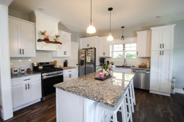 a kitchen with kitchen island granite countertop a stove and a wooden floors