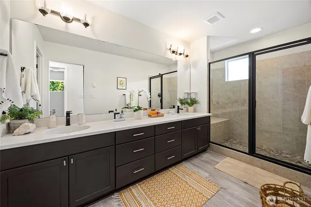 a bathroom with a double vanity sink a large mirror a shower and a bathtub