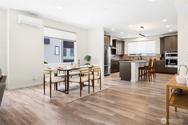 a dining hall with stainless steel appliances kitchen island granite countertop a dining table chairs and view living room