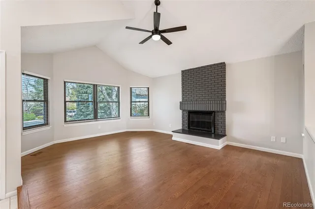 a view of an empty room with wooden floor fireplace and a window