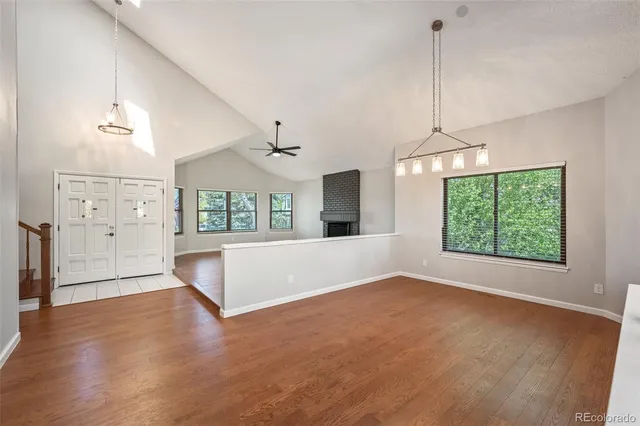 a view of an empty room with window and wooden floor