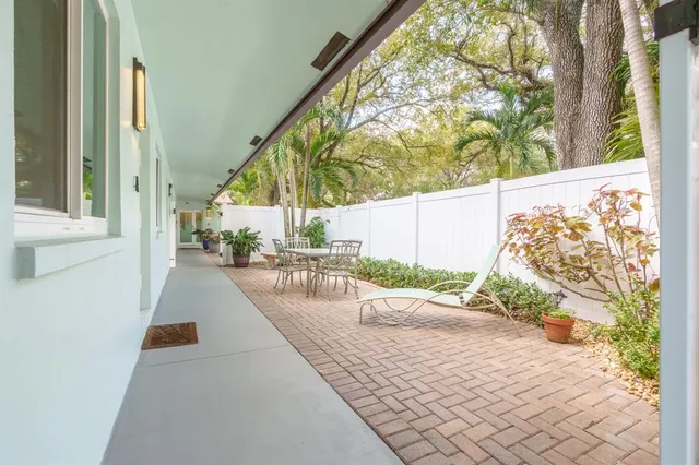 a patio with table and chairs and potted plants