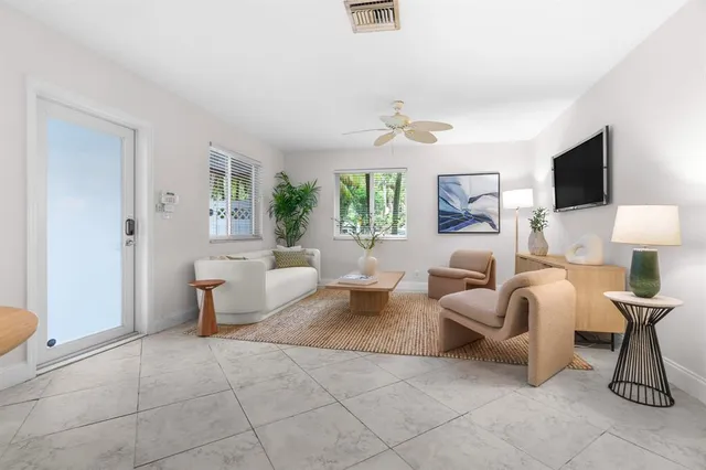 a living room with furniture a ceiling fan a rug and a window