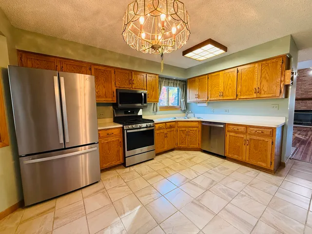 a kitchen with stainless steel appliances granite countertop a refrigerator a sink dishwasher stove and oven