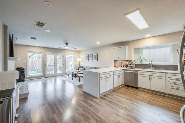 a large white kitchen with lots of counter space a sink dishwasher and a stove with wooden floor