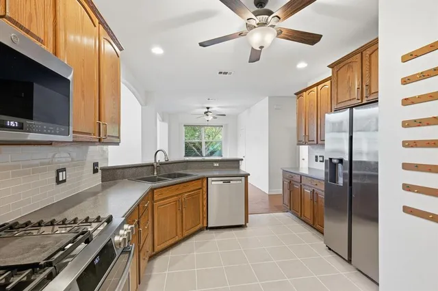a kitchen with stainless steel appliances granite countertop a sink a stove top oven a refrigerator with grey cabinets